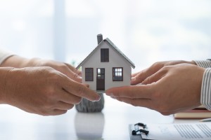 Vendita Casa 300x200 Vista di mani di due persone che si contendono il modellino di una casa